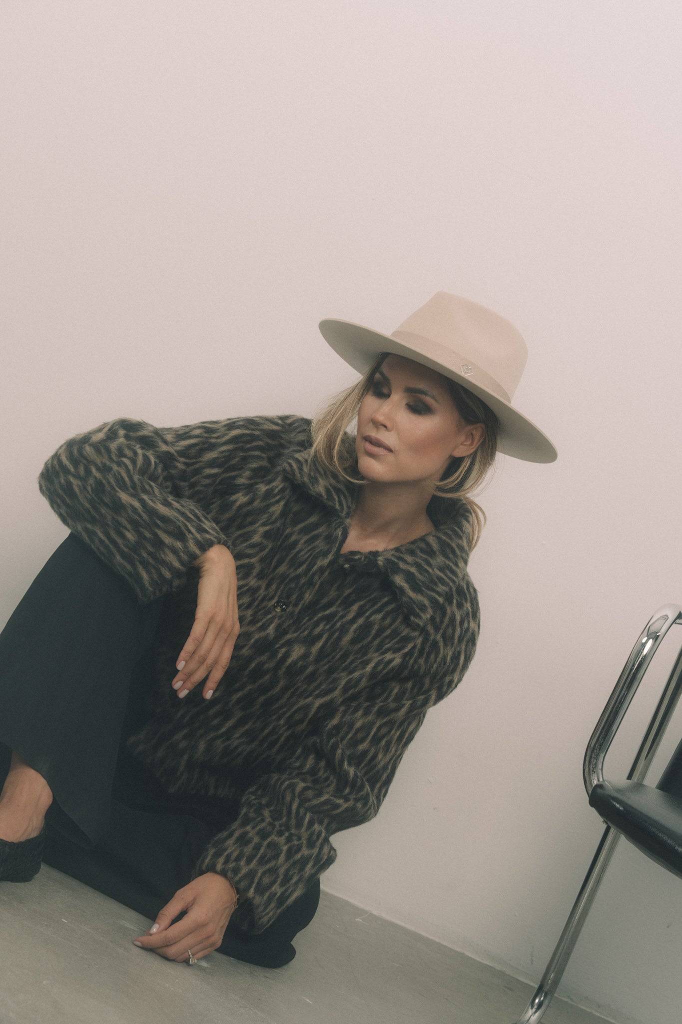 Designer cream fedora hat with a monogram detail, worn with a leopard-print coat. A timeless couture fedora for an elegant and modern look.