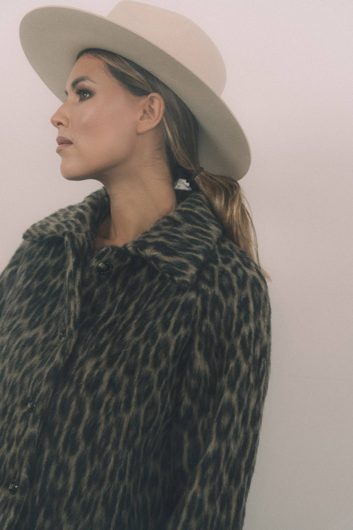 Side profile of a model wearing a cream fedora hat with a Petersham ribbon. A handcrafted rabbit fur felt hat for a refined and polished look.
